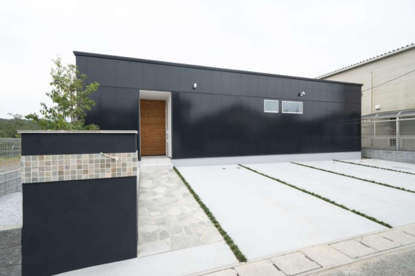 黒い外壁と白い玄関アプローチのコントラストが美しい平屋
