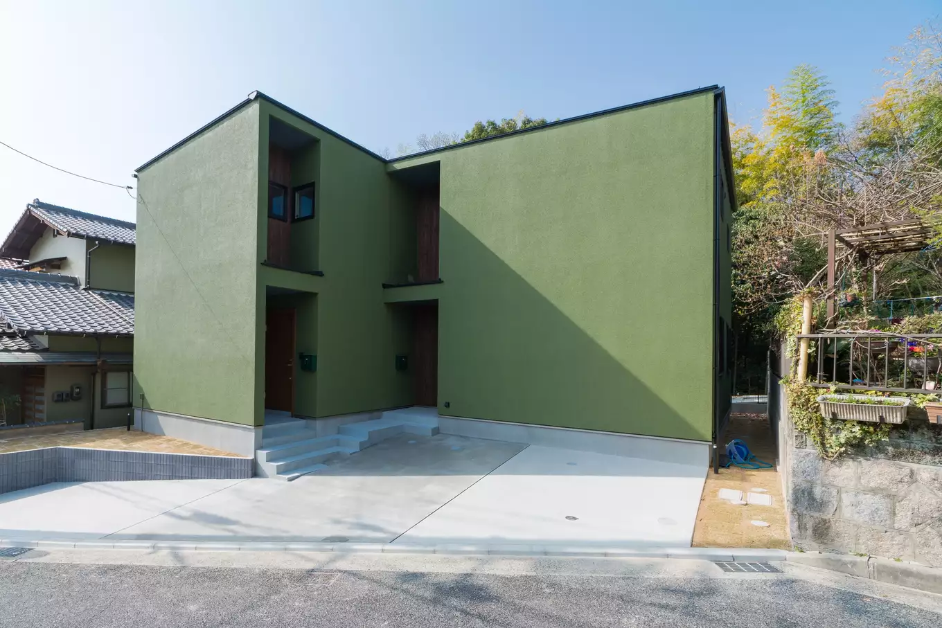 R+houseの建築事例写真。緑色の塗壁の2階建て住宅。完全分離型の二世帯住宅の為玄関が二つある。