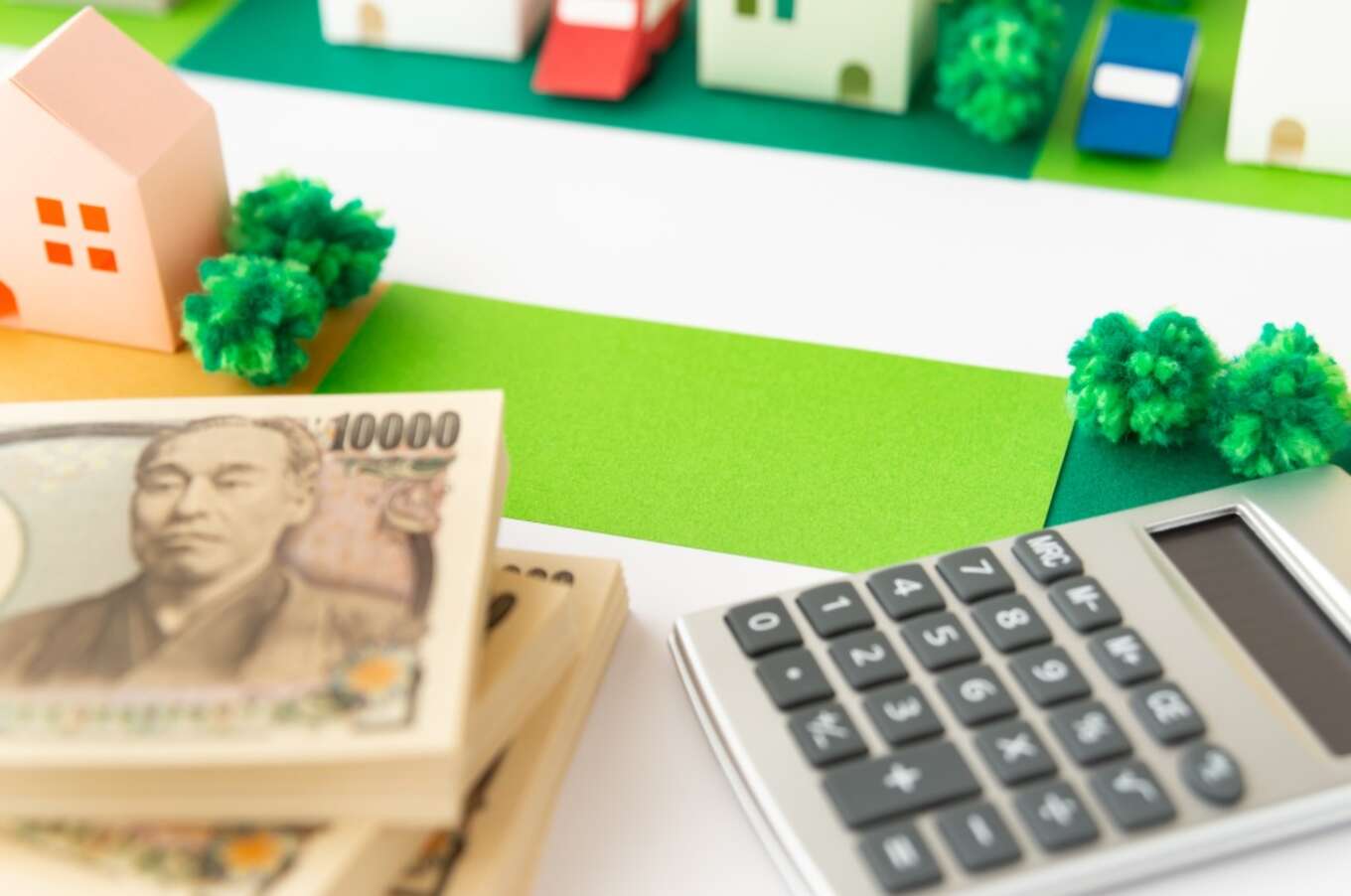 街の模型に置かれたお金と電卓