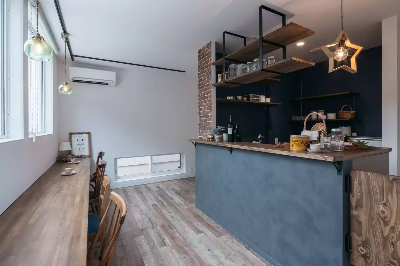 腰壁がグレーのカフェのようなおしゃれな木目調のキッチンと窓際のカウンター