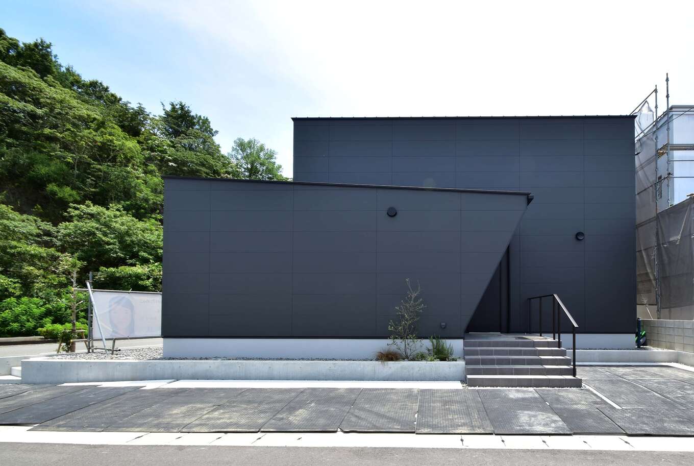 窓のないシンプルな黒い外壁の家