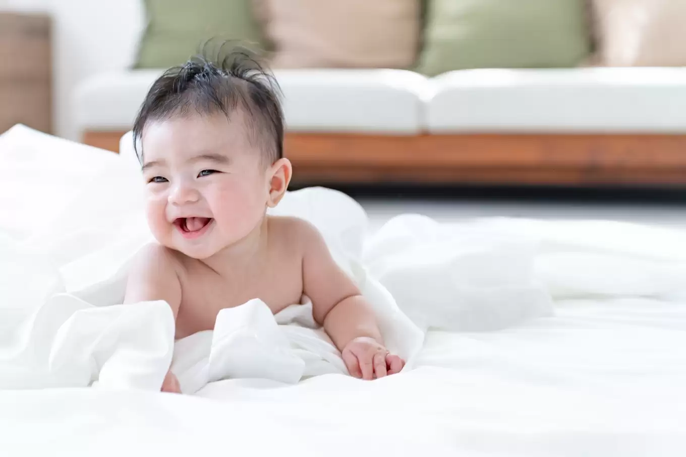 肌かん坊の赤ちゃんがタオルにくるまれて笑っている