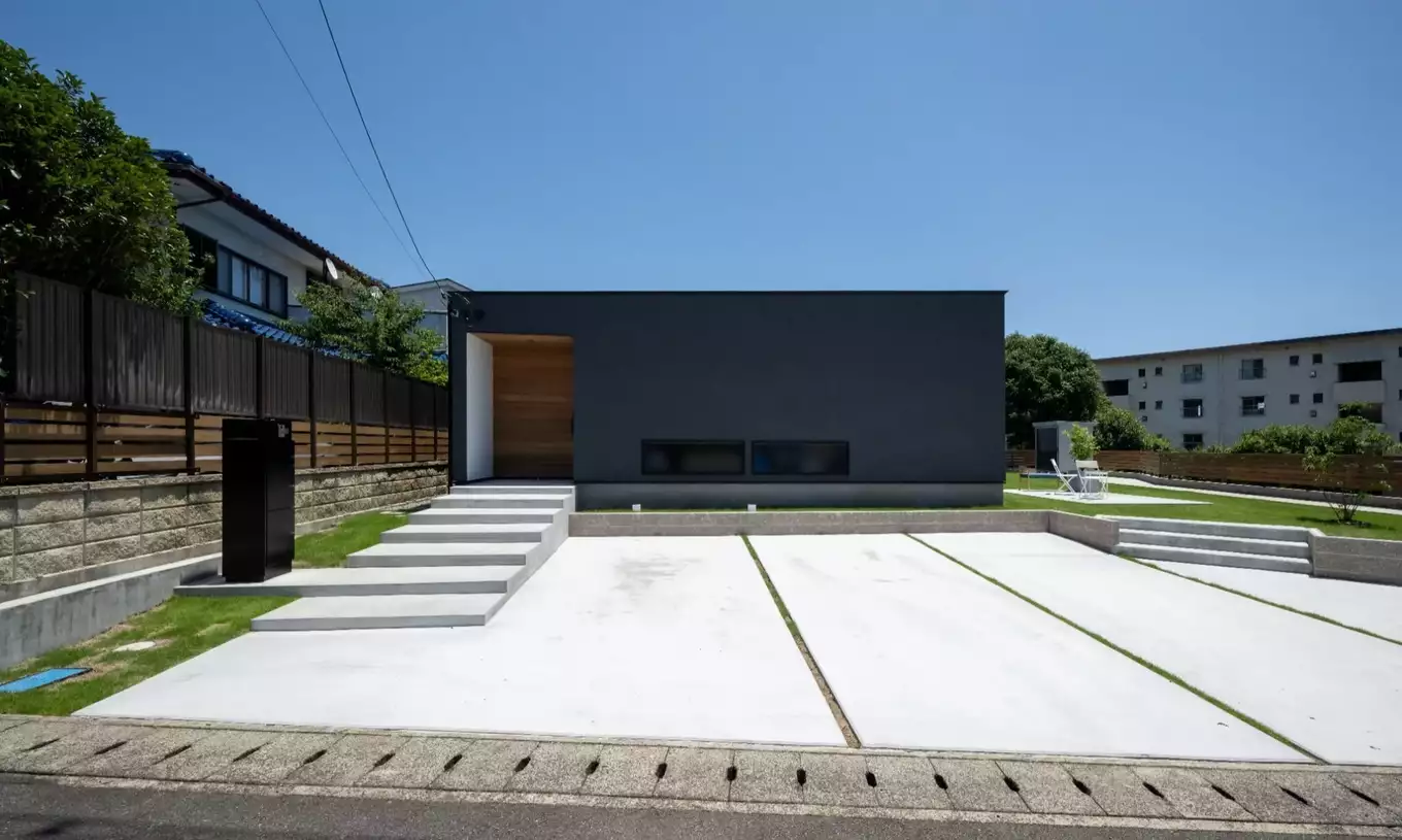 広い駐車場のあるシンプルな黒い平屋の家