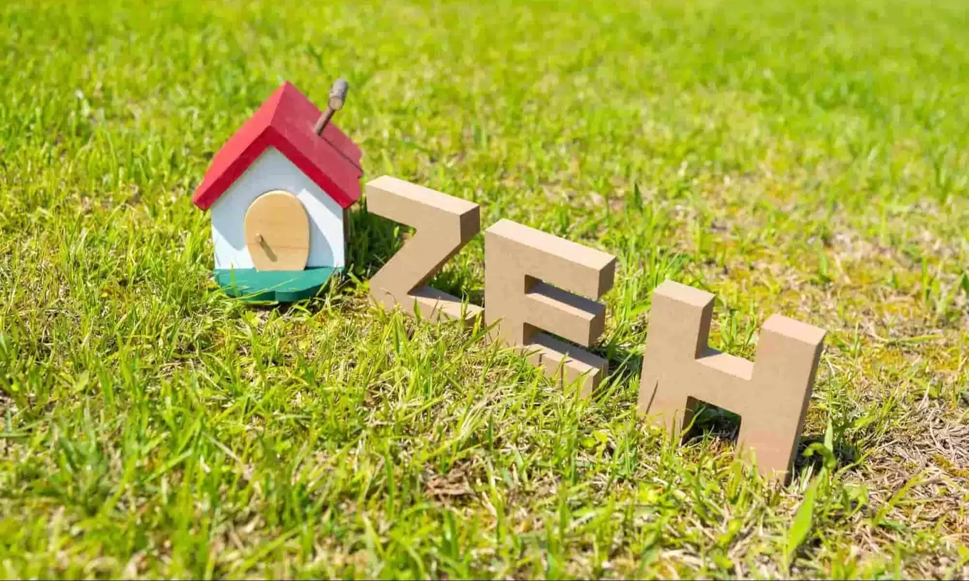 緑の芝に建つ小さな家とZEHのテキスト