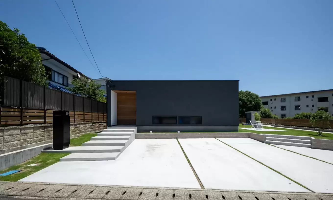 広い駐車場のあるシンプルな黒い平屋の家