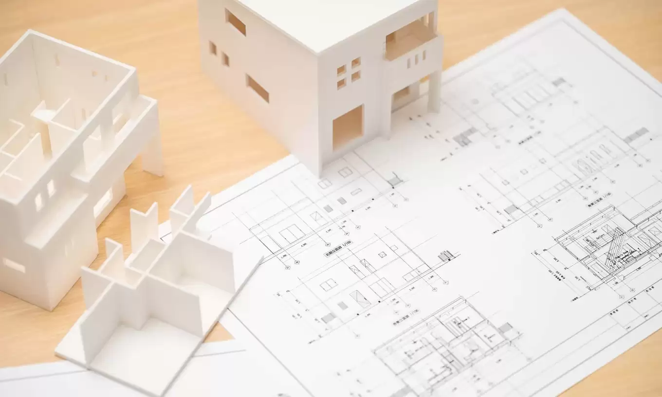 机の上に置かれた設計図面と住宅模型