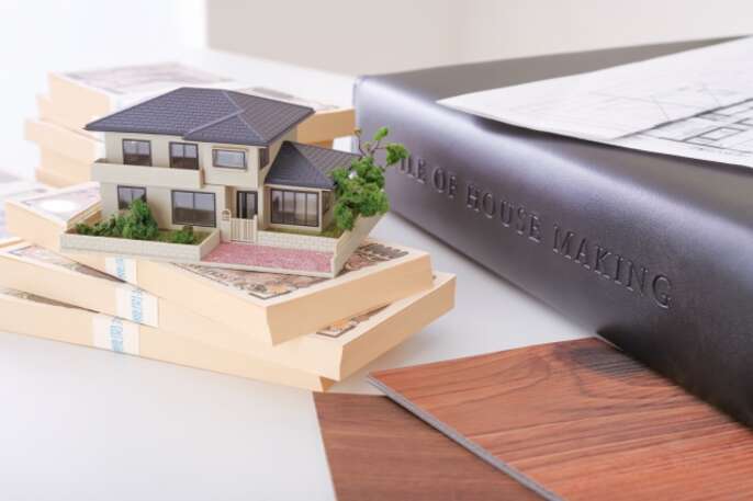 住宅打合せのイメージ。設計図と住宅模型、札束が映っています。
