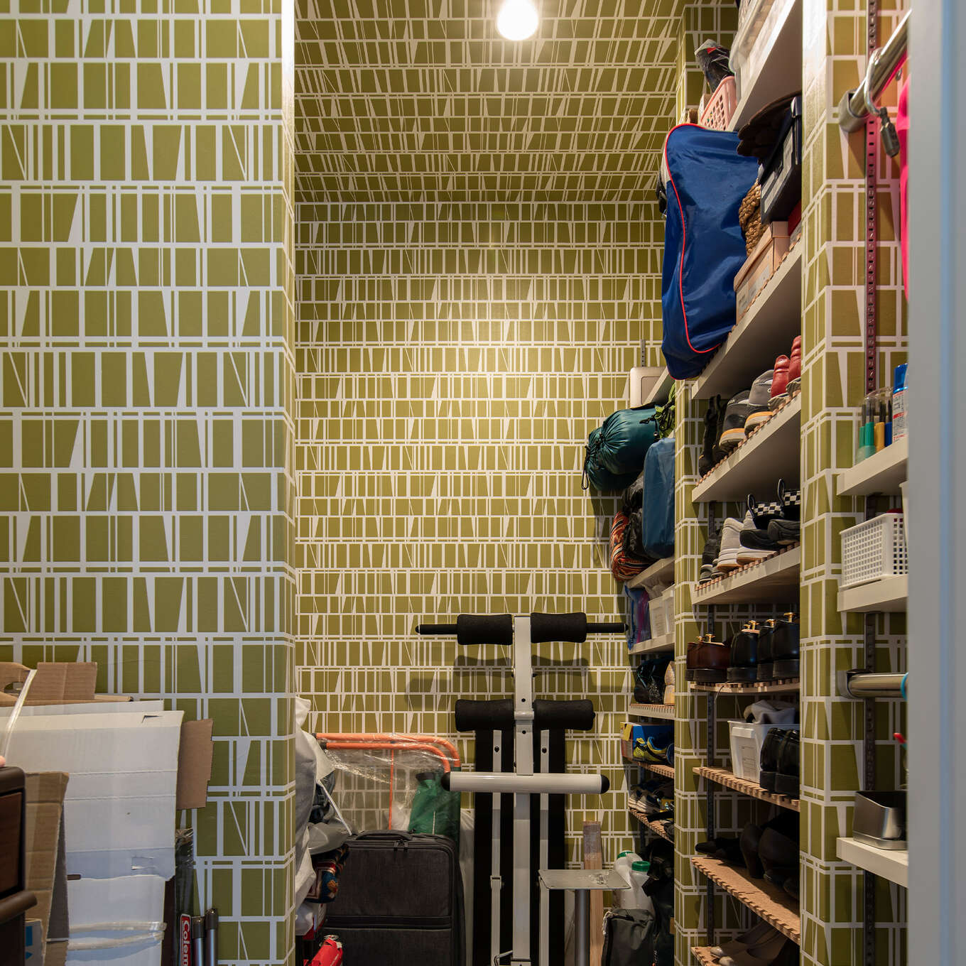 R+houseの物件のシューズインクローゼットの写真です。緑色の模様が入った壁紙は天井まで続いて一体感を生む。右側は棚になっており靴をしまえ、左側は何でも置ける空間に。