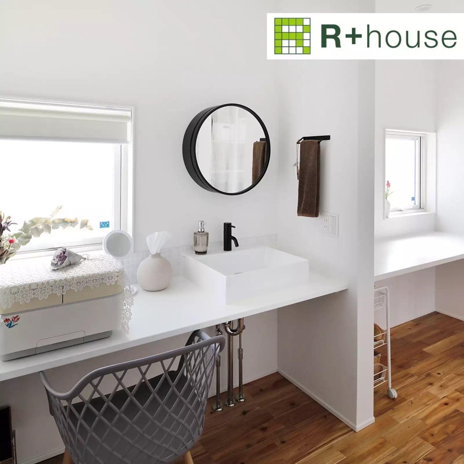 R+houseの物件のワークスペース横の洗面台の写真です。カウンターにつけられた白が基調の洗面台、壁にかかる黒い丸鏡がアクセント