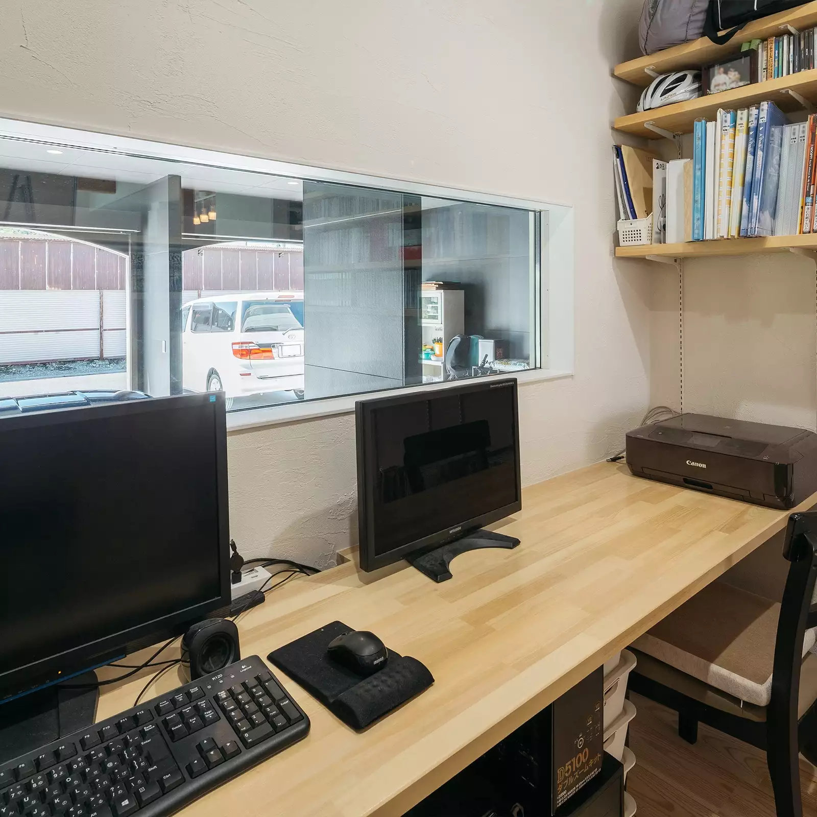 R+houseの物件の書斎の写真です。備え付けの机があり座った時目線の高さにはガレージがのぞける横長の窓。右には備え付けの棚が。