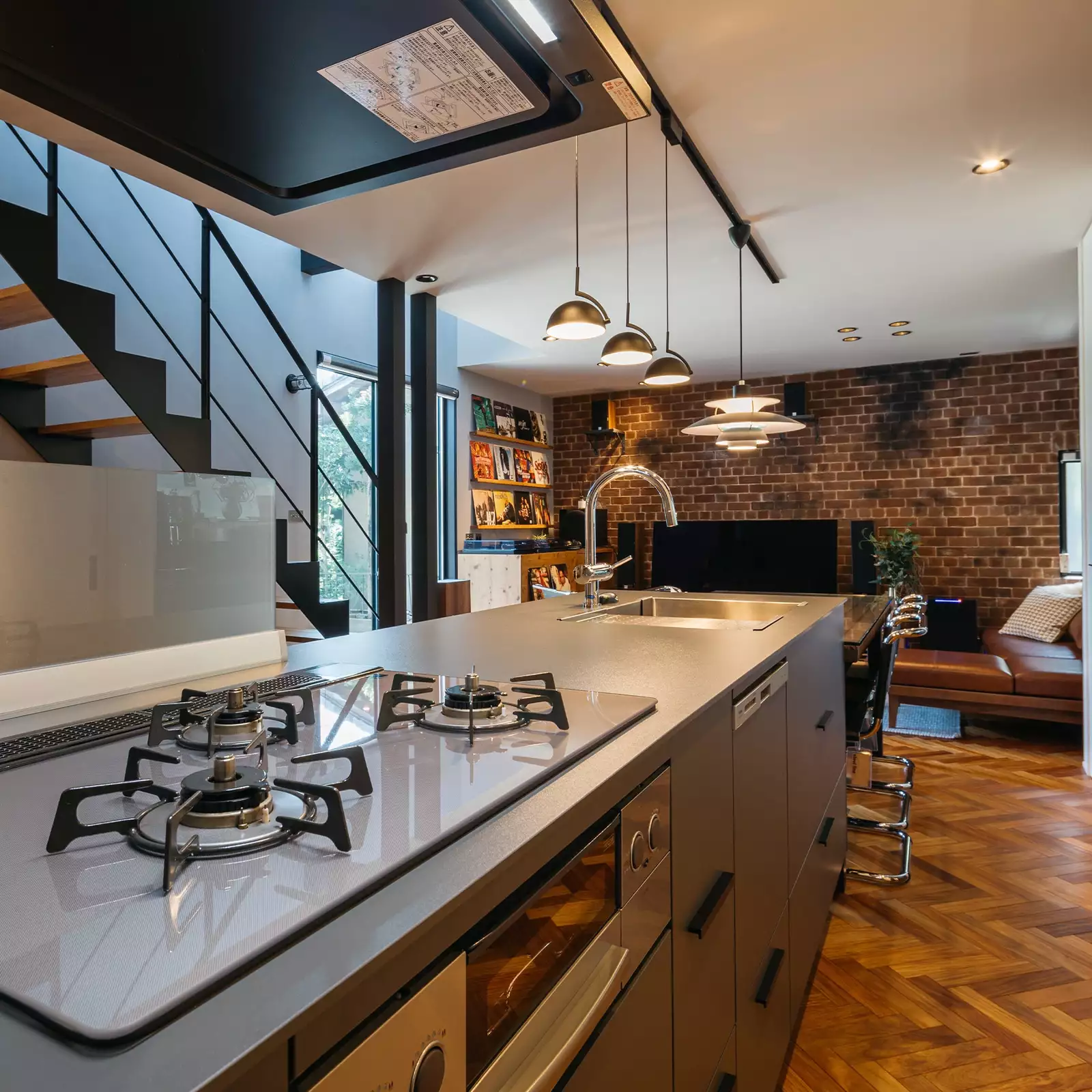 R+houseの物件のキッチンの写真です。アイランドキッチンのよこにダイニングテーブルが繋がる。キッチンからは洗面室や階段、リビングが見渡せる。