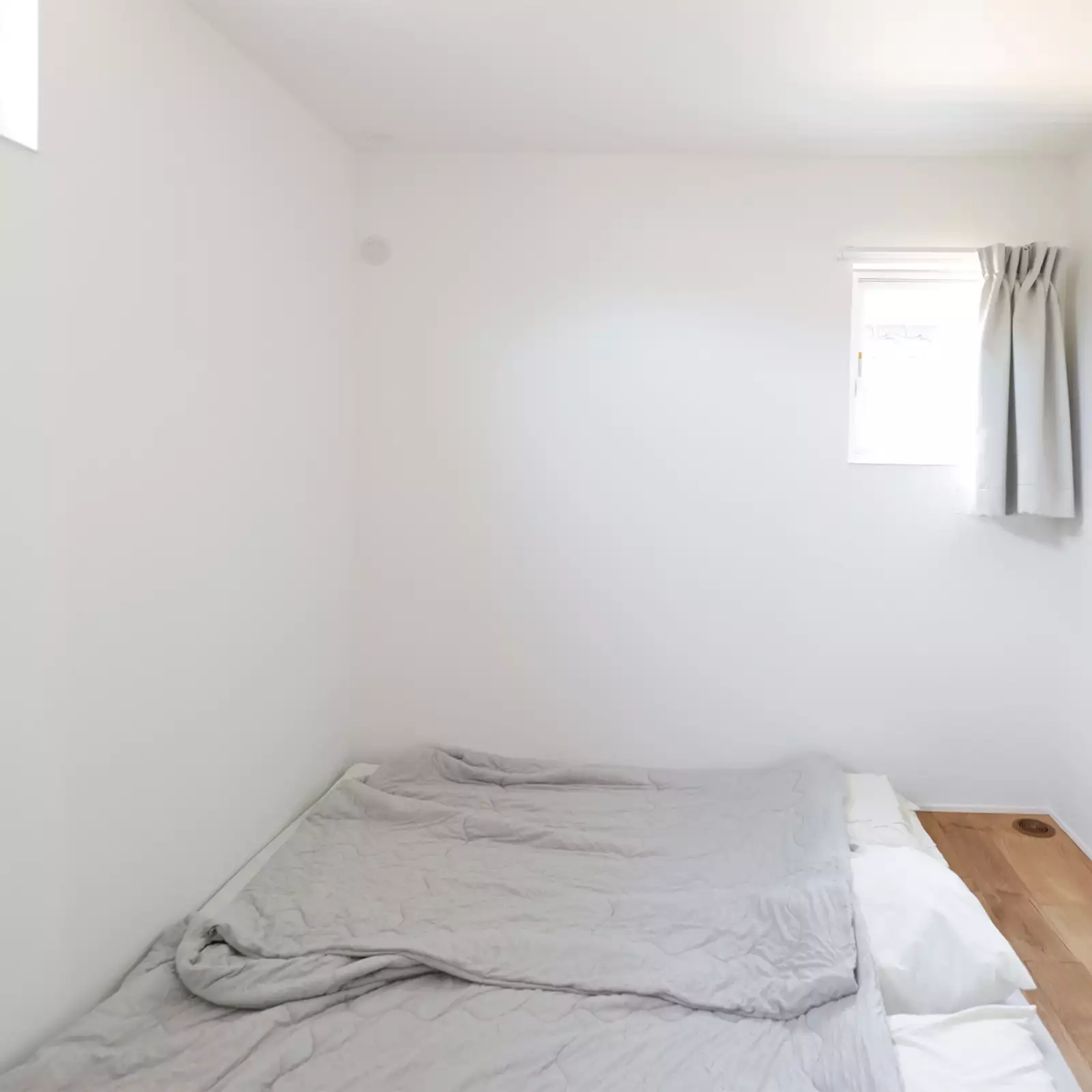 R+houseの物件の寝室の写真。小さな窓が上部についているだけのシンプルなお部屋。
