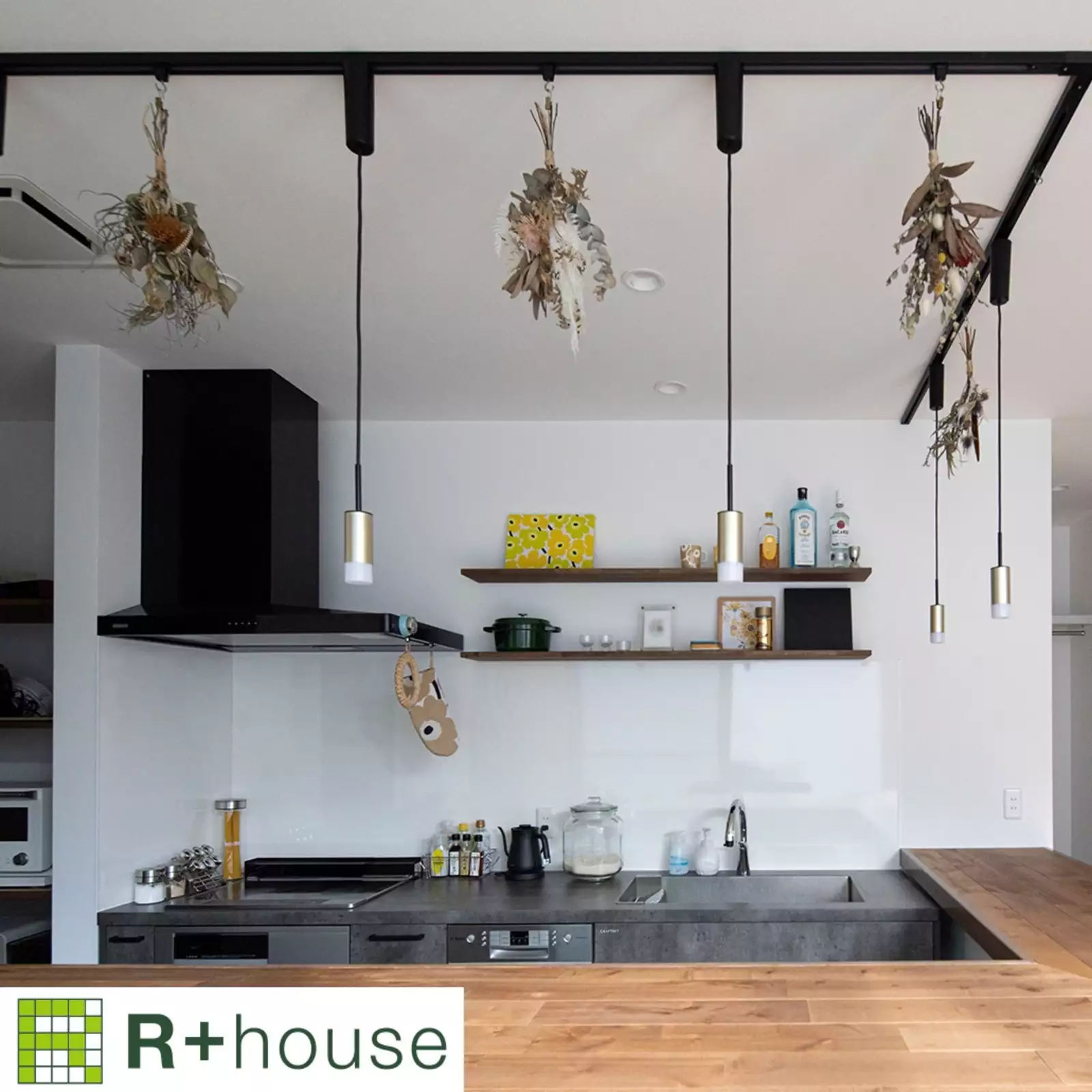 R+houseの物件のカウンターキッチンの写真です。L字型のカウンターキッチン白の壁にグレーのキッチン台、木目のカウンターが際立つ