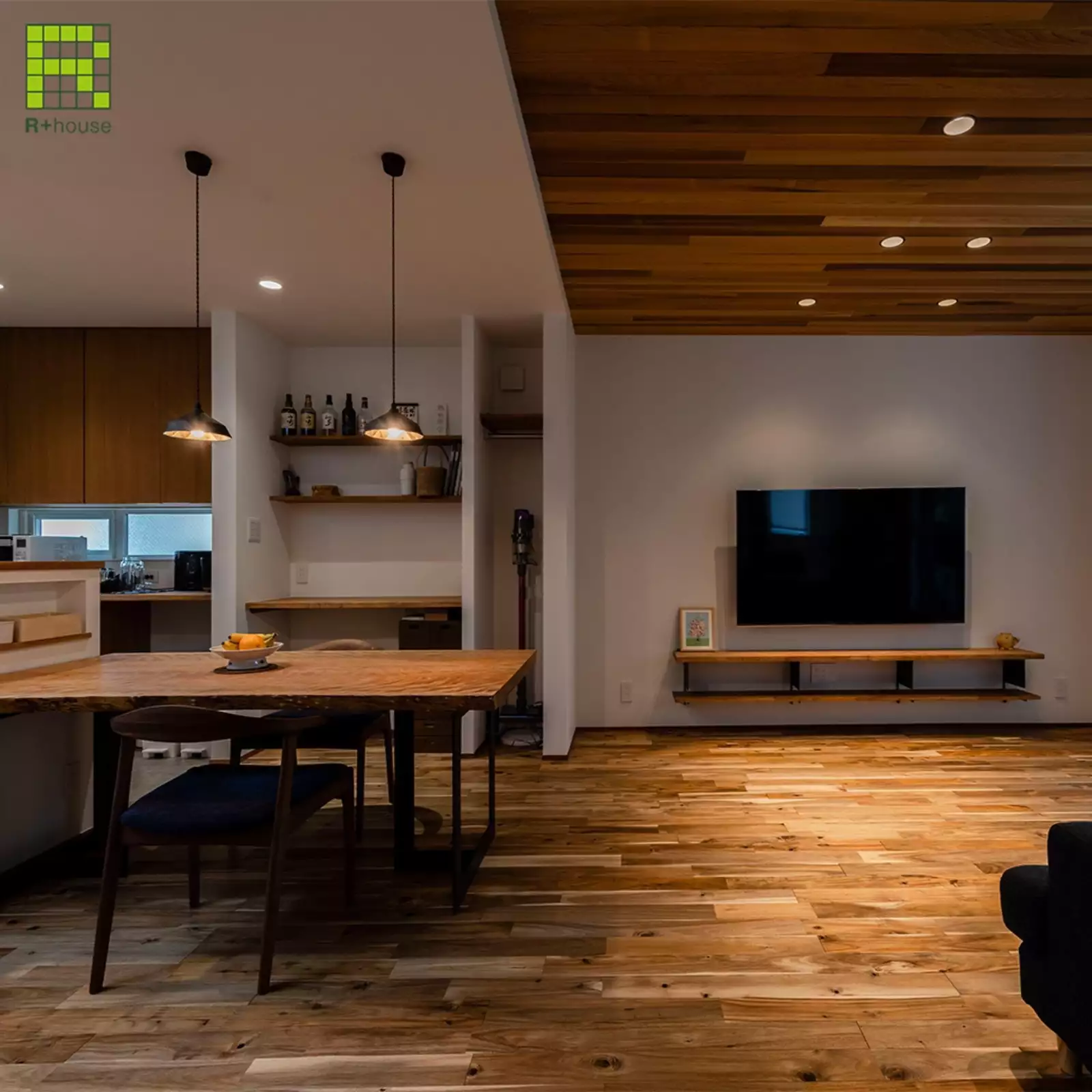 R+houseの物件のリビングダイニングの写真です。左側にはキッチン、ダイニングテーブル。右側に木目の床が印象的なリビング。