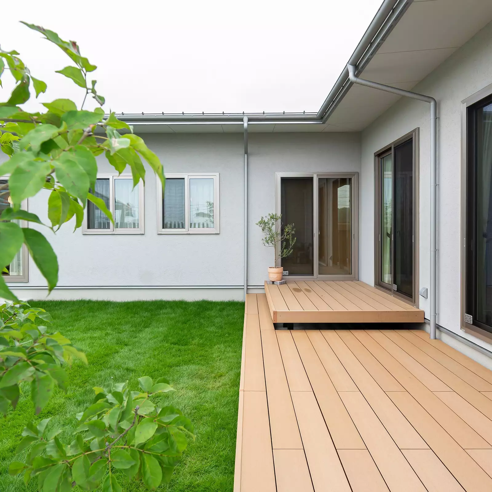 R+houseの物件の庭の写真です。左に芝生で覆われた庭、右に大きなウッドデッキがあります。