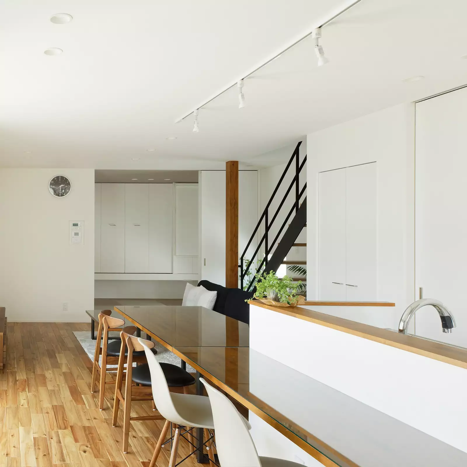 R+houseの物件のリビングダイニングの写真です。木目と白を基調とした室内に黒色の家具や階段が映えます