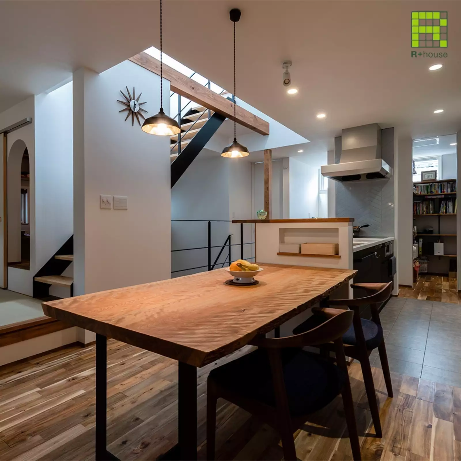R+houseの物件のダイニングキッチンの写真です。奥には約2畳の書斎、手前にキッチンとダイニングテーブル。キッチンの前には階段が。