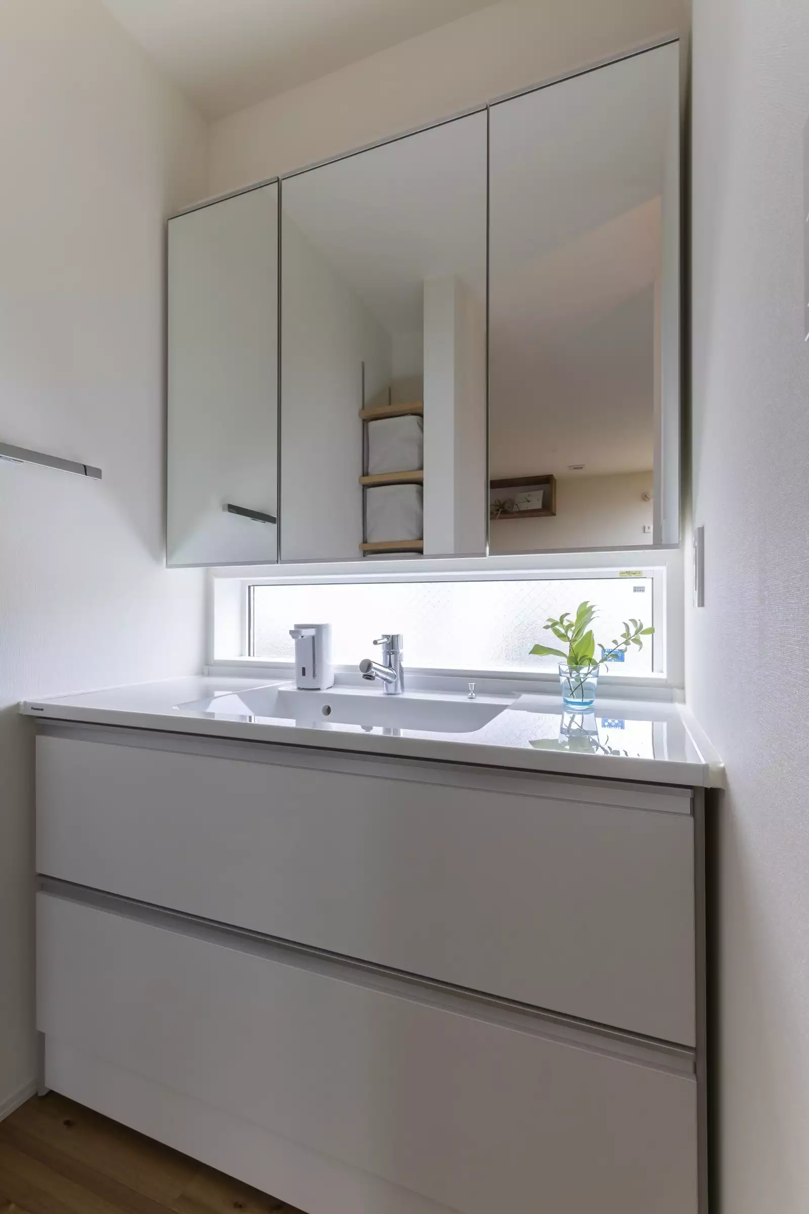 洗面室は白で統一。ミラーと洗面台の間にある窓がアクセント。