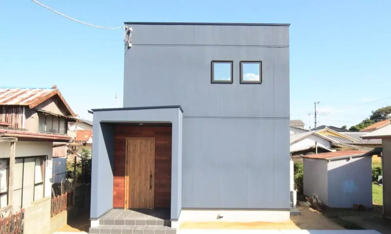 グレー色の吹き付け塗装の外壁とレッドシダー張りの家