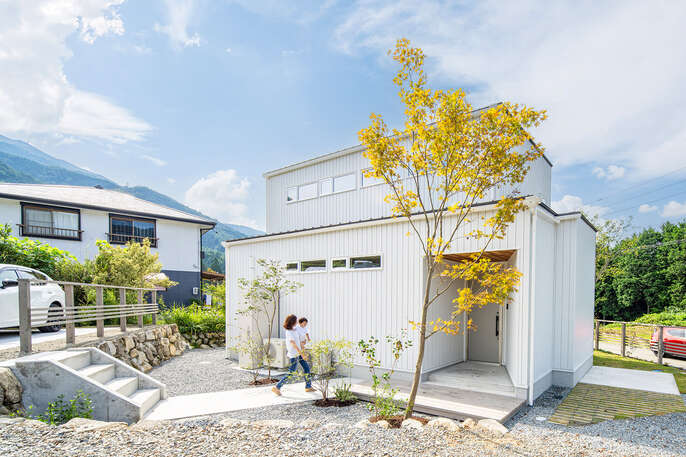 R+house飛騨モデルハウスの外観の写真。周辺の自然と植えられた植栽に白いガルバリウムの外壁が映える。