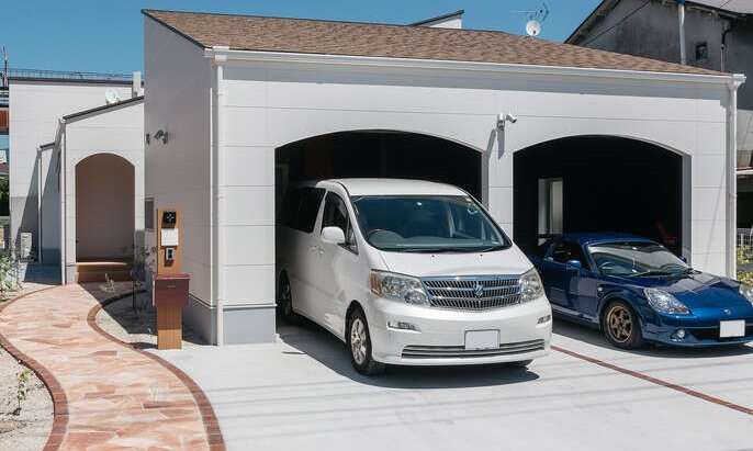R+houseの物件の写真です。車が2台停められるガレージ。外観は温かみを感じるプロヴァンス風のデザイン。テラコッタタイルを敷き詰めたアプローチ。