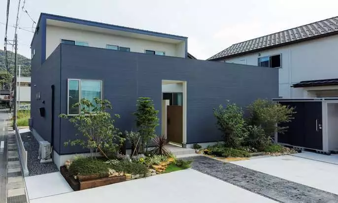 R+houseの物件の写真です。紺色と白色のツートンカラーの家。玄関の前には素敵な花壇があります。