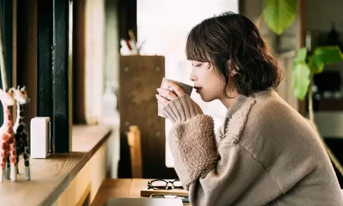 窓辺でのんびりコーヒータイムを楽しむ女性