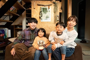 ソファに座って笑顔でくつろぐ家族の様子